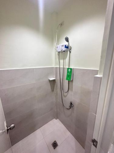 y baño con ducha y una señal verde en la pared. en Travelbee Airport Inn en Isla de Mactán