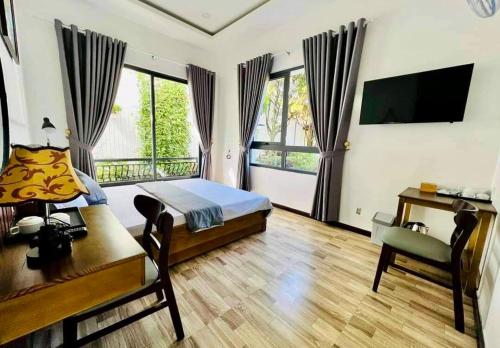 a bedroom with a bed and a desk and a television at Hotel Hoa Nắng in Bao Loc