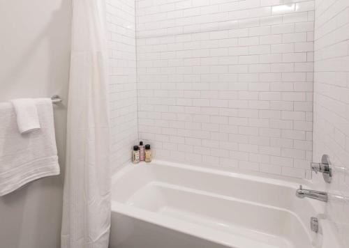 ein weißes Bad mit weißer Badewanne und weißen Fliesen in der Unterkunft Cozysuites l Prime 1BR in Downtown Cincinnati in Cincinnati