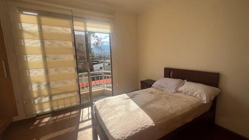ein Schlafzimmer mit einem Bett und einem großen Fenster in der Unterkunft Departamento moderno con gran espacio in Cuenca