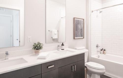 Baño blanco con lavabo y aseo en CozySuites Stunning 3BR in Downtown Cincinnati, en Cincinnati