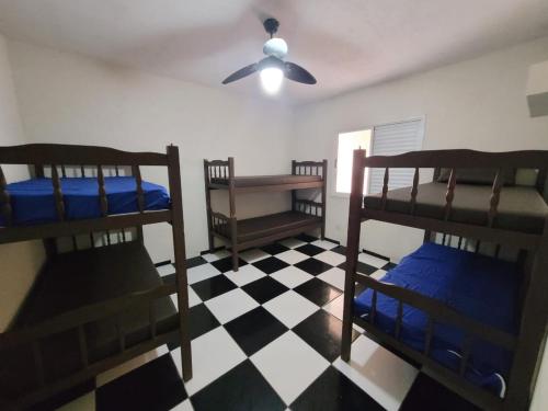 a room with three bunk beds on a checkered floor at CASA 50 metros DA PRAIA Matinhos in Matinhos