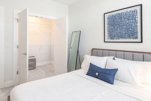 a white bedroom with a blue pillow on a bed at Cozysuites l Luxe 2BR in Downtown Cincinnati in Cincinnati