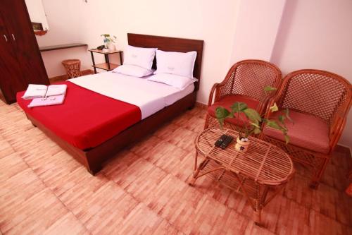 a bedroom with a bed and two chairs and a table at Rays Inn Thekkady in Thekkady