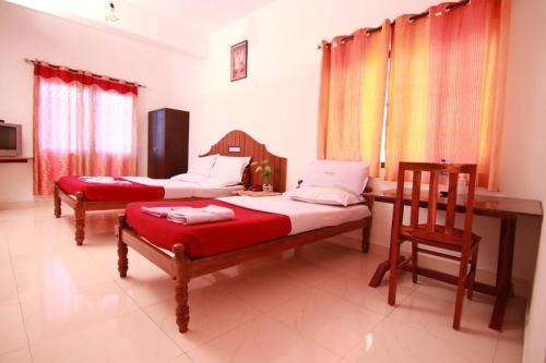 a room with two beds and a table and chairs at Rays Inn Thekkady in Thekkady