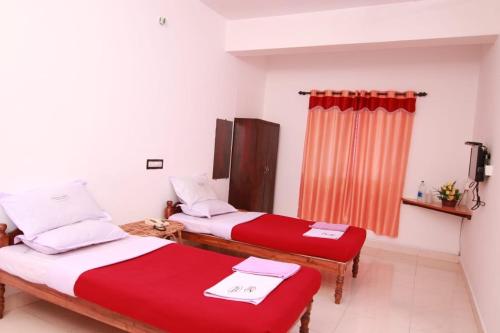 two beds in a room with red and white sheets at Rays Inn Thekkady in Thekkady