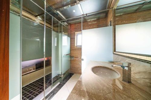 ein Bad mit einem Waschbecken und einer Glasdusche in der Unterkunft Along the River B&B in Dongshan