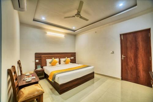 a bedroom with a bed and a table and a door at HOTEL VISA INN NEAR KEMPEGOWDA AIRPORT in Bangalore