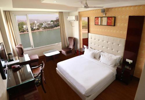 a bedroom with a white bed and a large window at Ganga Exotica in Haridwār