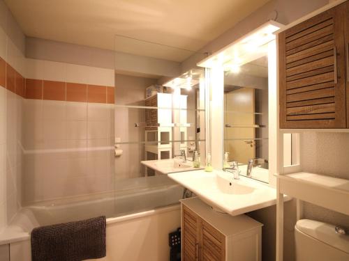 une salle de bain avec un lavabo, un miroir et une baignoire dans l'établissement Charmant T2 Bis avec Wi-Fi, Proche Thermes et Commodités à La Bourboule - FR-1-608-266, à La Bourboule