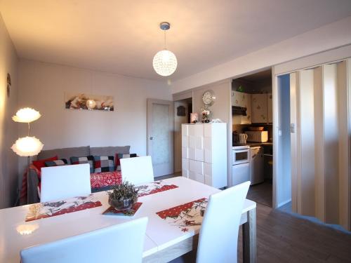 une cuisine et un salon avec une table et des chaises blanches dans l'établissement Bel Appartement T2 avec Balcon et Wifi au Mont-Dore - FR-1-608-267, à Le Mont-Dore