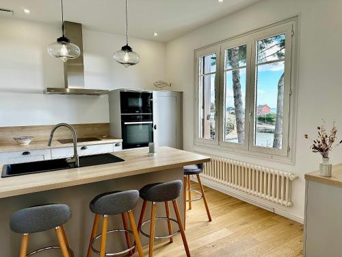 une cuisine avec un îlot et des tabourets de bar dans l'établissement Maison grand confort à Doëlan, vue mer, accès chemins côtiers et plage, WIFI, parking - FR-1-714-12, à Clohars-Carnoët