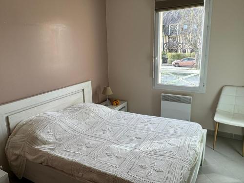 - une chambre avec un lit doté d'une couette blanche et d'une fenêtre dans l'établissement Appartement Moderne près de la Plage et du Centre - 2 Chambres, Balcon, Parking, Animaux Acceptés - FR-1-487-363, à Cabourg