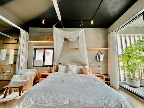 ein Schlafzimmer mit einem großen Bett in einem Zimmer mit Fenstern in der Unterkunft 隱室x迷路 Hermit Inn Hengchun in Altstadt von Hengchun