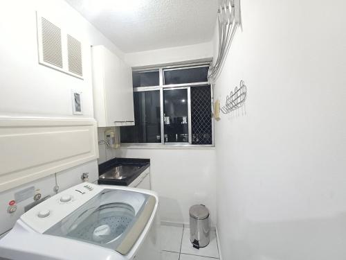 uma casa de banho branca com um lavatório e uma janela em Apê UNIFA-EsSLog Condomínio com estacionamento no Rio de Janeiro