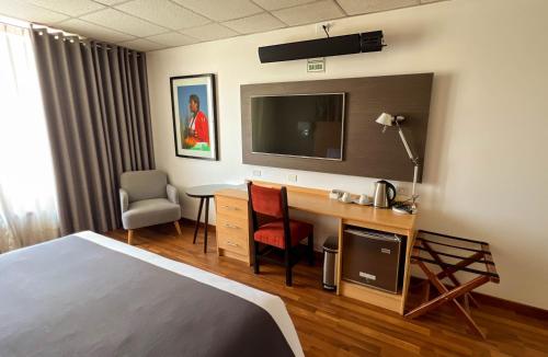 a hotel room with a bed and a desk with a television at Lake Titicaca Hotel in Puno