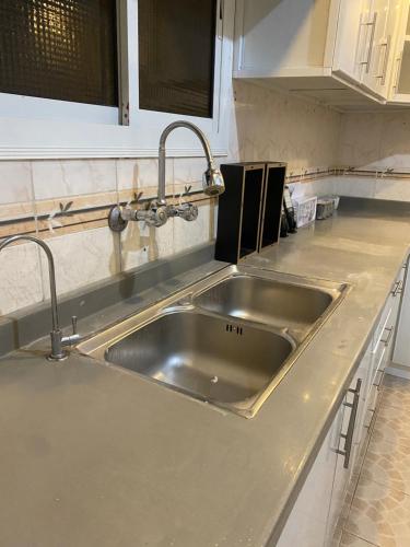 - un évier en acier inoxydable dans une cuisine avec des placards blancs dans l'établissement العلم نور2, à Sīdī Ḩamzah