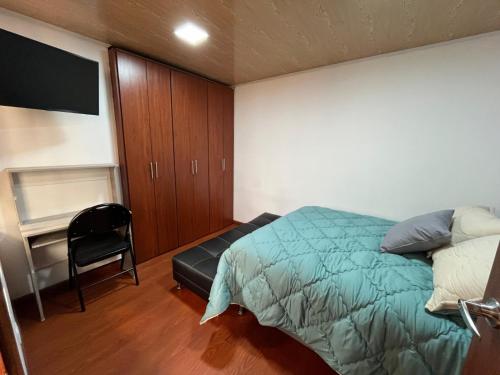 um quarto com uma cama, uma cadeira e uma secretária em Apartamento en Normandia a 10 minutos del aeropuerto em Bogotá