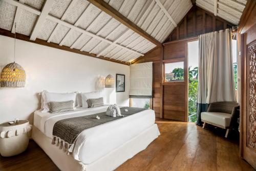 ein Schlafzimmer mit einem großen weißen Bett und einem Stuhl in der Unterkunft House of Bagera by Alfred in Bali in Seminyak