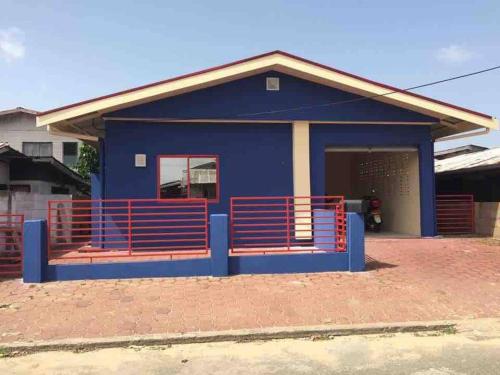 a blue house with a red fence in front of it at Cozy Home in Paramaribo