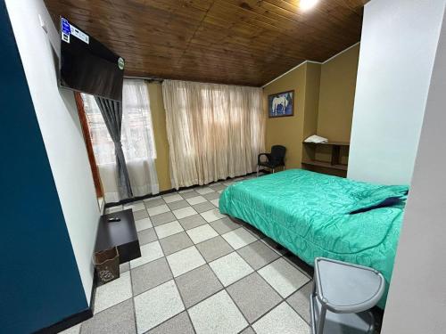 Schlafzimmer mit einem grünen Bett und einem Schreibtisch in der Unterkunft Villa Antonio in Zipaquirá
