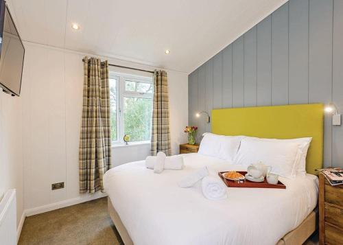 a bedroom with a large white bed with a tray on it at Wareham Forest Lodge Retreat in Lytchett Minster