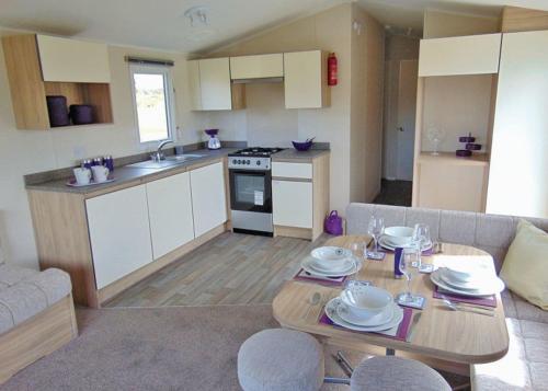 a kitchen and a living room with a table and a couch at Ty Gwyn Park in Abergele