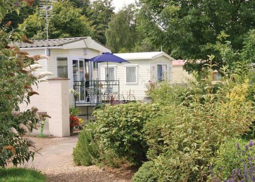 a small white house with a blue umbrella at Silver Birch Caravan Park in Talacre