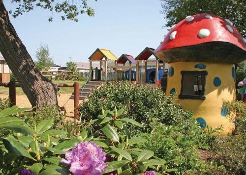 een speelpark met een speelstructuur met een paddestoel bij Silver Birch Caravan Park in Talacre