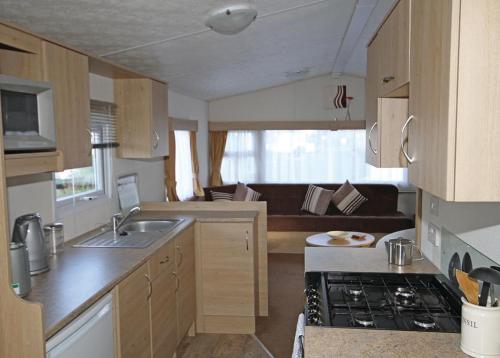 a kitchen with a sink and a stove in a room at Silver Birch Caravan Park in Talacre