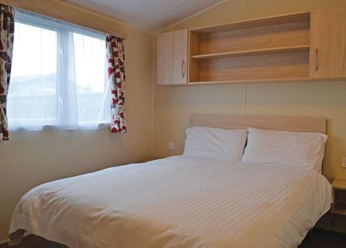 a bedroom with a white bed with a window at Pencnwc Holiday Park in Llanllwchaiarn