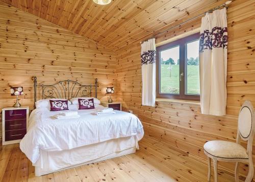 1 dormitorio con 1 cama en una habitación de madera en Trewythen Lodges en Caersws