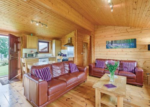 uma sala de estar com sofás de couro e uma mesa em Trewythen Lodges em Caersws