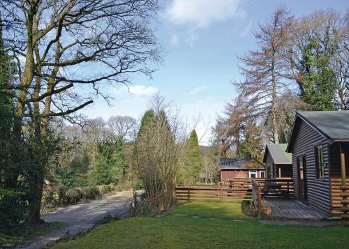 a log cabin with a fence and a house at Ruthern Valley Holidays in Lanivet