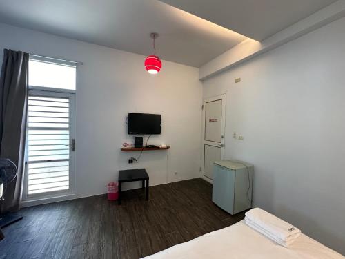 a bedroom with a bed and a tv on the wall at Snore Inn in Hengchun