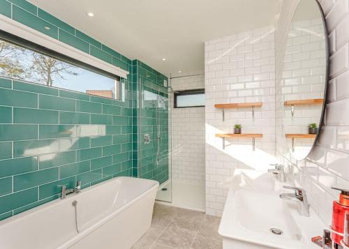 a bathroom with a tub and a sink and a mirror at Swanborough Lakes in Lewes