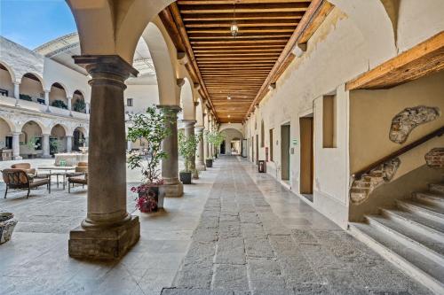 an arcade with columns and tables in a building at Quinta Real Puebla in Puebla