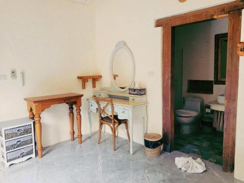 a bathroom with a vanity with a mirror and a toilet at Swiss Hotel Pattaya in Sattahip