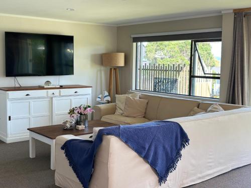 a living room with a couch and a tv at Sea View Apartment in Whangaparaoa