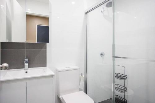 La salle de bains est pourvue de toilettes et d'une douche en verre. dans l'établissement NEW! Ideal 1BR Unit in the Hot Spot of Surry Hills, à Sydney