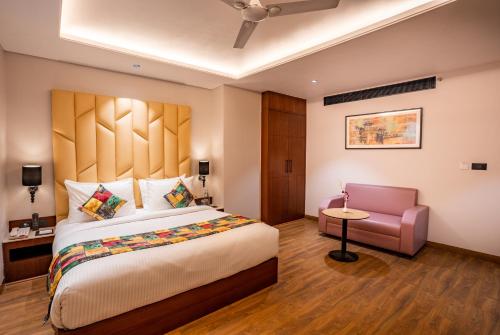 a bedroom with a large bed and a chair at Regenta Place Raaj Agra in Agra