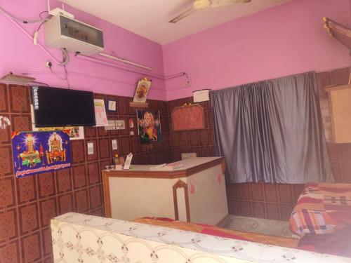 a room with purple walls and a tv and a couch at Sri Kanya Residency, Srikalahasti in Srikalahasti