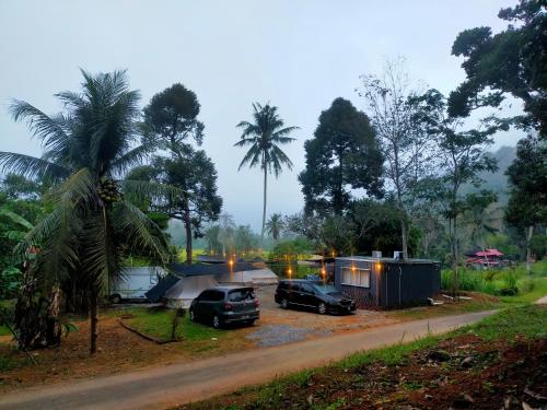 a couple of cars parked next to a house at Tanah Merah Glamping Village (TMGV) in Kuala Kangsar