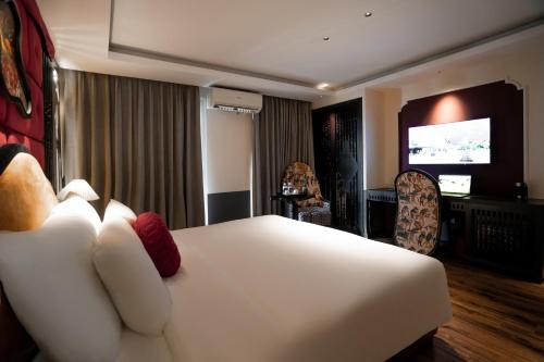 a hotel room with a white bed and a television at Hanoi Center Silk Classic Hotel & Travel in Hanoi