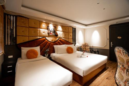 a hotel room with two beds and a chair at Hanoi Center Silk Classic Hotel & Travel in Hanoi