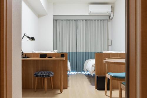 yksi STAY ＆ APARTMENT OSAKA في أوساكا: غرفة مستشفى بسرير وطاولة وكراسي