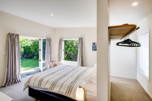 a bedroom with a bed and two windows at Garden Retreat - Napier Holiday Home in Napier