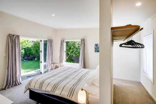 a bedroom with a bed and two windows at Garden Retreat - Napier Holiday Home in Napier