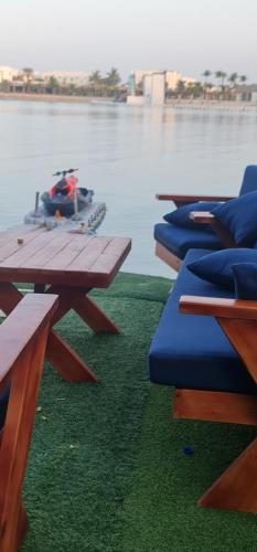 a group of picnic tables with a boat in the water at فيلا بشاطئ خاص ومسبح in Durat Alarous