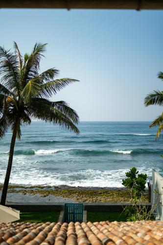 a view of a beach with a palm tree and the ocean at Nil Ralla in Talpe